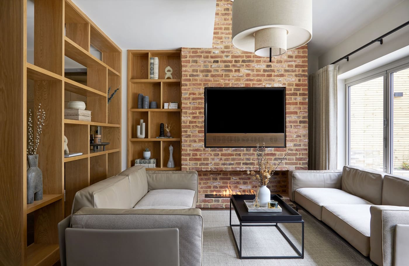 Living room with built-in shelving and exposed brick by Construction Eye